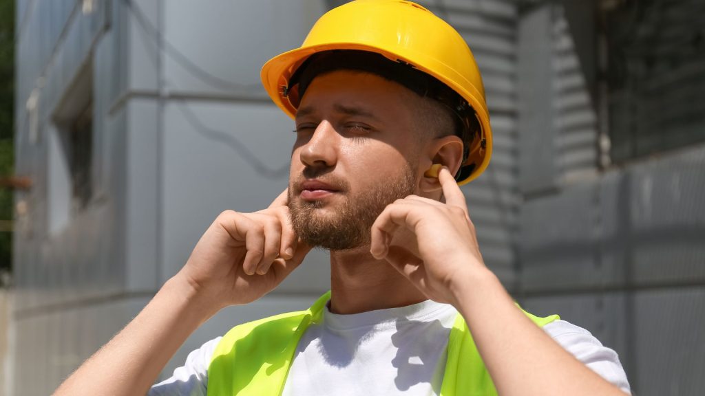 Travailleur sur un chantier portant des protections auditives pour éviter les troubles auditifs